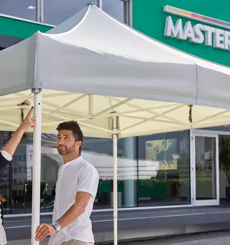 Two people view a canopy tent.