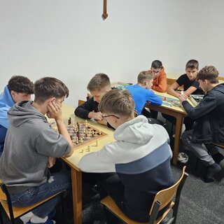 An zwei Tischen spielen jeweils 4 Schüler gemeinsam ein Brettspiel.